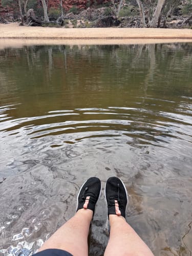 Reviewer's black Women's Xdrain Vibe shoes being worn while wading in shallow water outdoors.