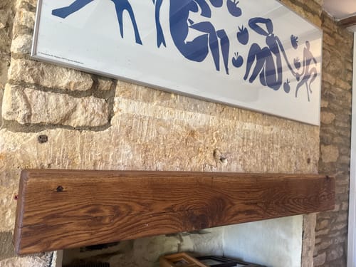Customer's Rustic Oak Fireplace Beam installed as a floating mantel above a stone fireplace.