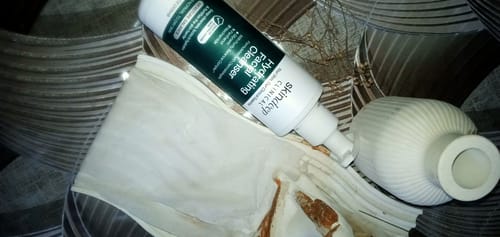 Reviewer's Hydrating Facial Cleanser bottle resting on a white surface with curved decorative objects.