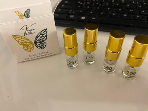 Kunden-Testerset mit vier kleinen Parfumfläschchen mit goldenen Kappen und der zugehörigen Verpackung auf einem Tisch.