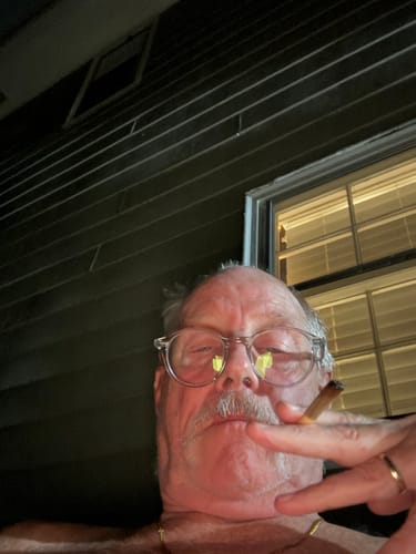 Customer's hand holding a Pre Rolls 100ct joint while looking at the camera.