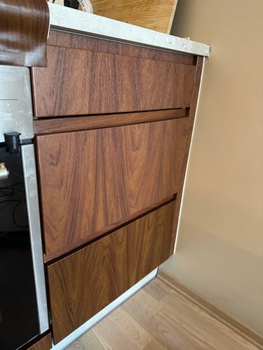 Reviewer's Walnut Deep kontaktplast montert på kjøkkenskuffer som viser tydelig fargeforskjell i trestrukturen.