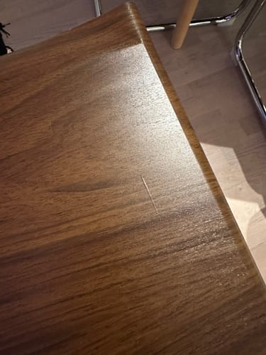 Reviewer's oversiktsbilde av Walnut Deep kontaktplast med synlig trestruktur og en liten ripe i overflaten.