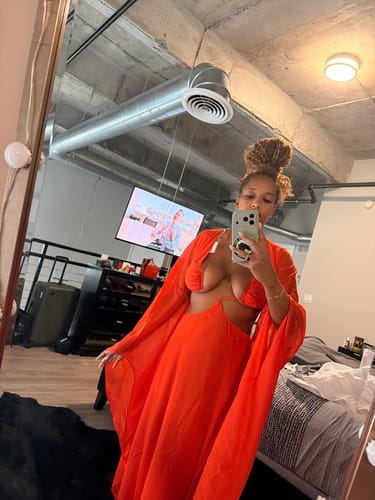 Customer wearing an orange Chiffon Cutout Maxi Dress, showing the halter neckline, waist cutouts, and flowing sleeves.