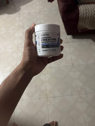 Customer's hand holding a white tub of Wellcore Micronised Creatine Monohydrate.