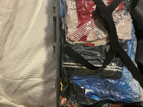 Customer's opened suitcase containing vacuum-sealed bags of folded clothing items.