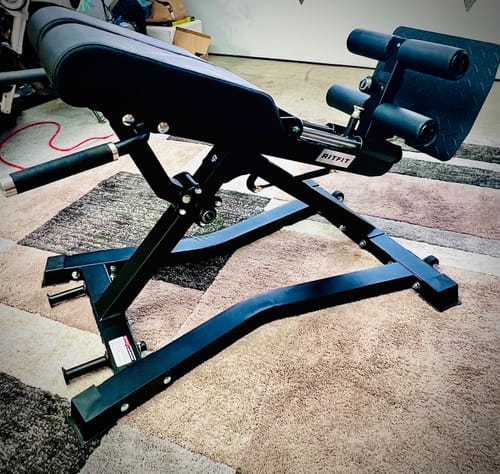 Reviewer's black RitFit Adjustable Back Extension Machine standing fully assembled on a rug in a home room.
