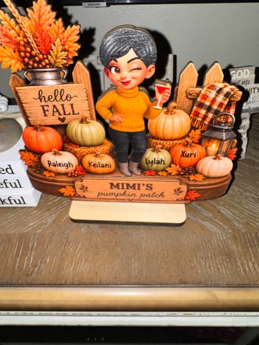 Customer's personalized Hello Fall wooden plaque featuring pumpkins with names, standing on a wooden base.