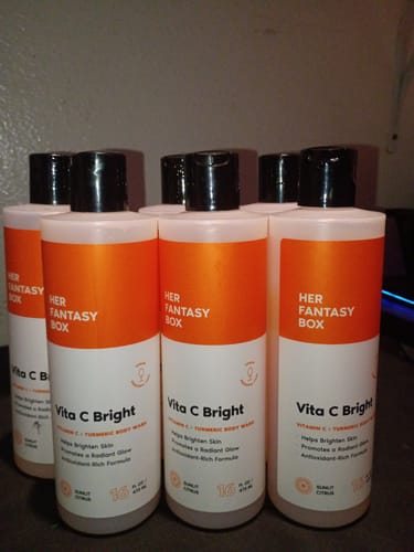 Customer's multiple orange bottles of Vita C Bright body wash grouped together on a flat surface.