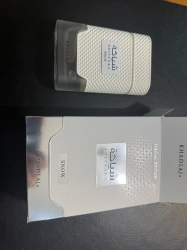 Customer's Khadlaj Shiyaaka Snow perfume bottle and open white rectangular box on a dark surface