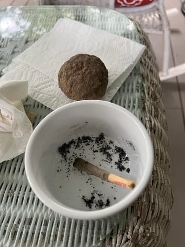 Customer's Pre Rolls 100ct, partially used, resting inside a small white bowl with ash