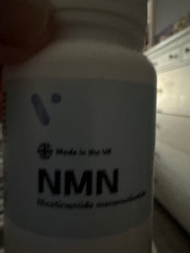 Gros plan flou d'un flacon de gélules Pure NMN 500 mg du client, avec la mention Made in the UK sur l'étiquette.