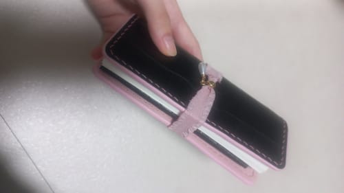 Reviewer's hand holding the Noir Rosé journal, featuring a black crocodile-textured cover with pink accents and a pearl.