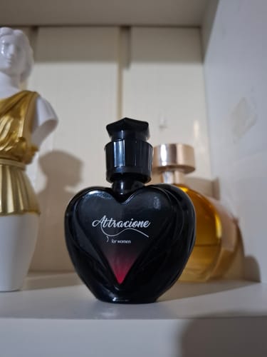 Customer's Attracione perfume bottle with heart-shaped design next to a statue piece.
