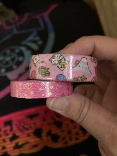 Customer's hand holding two rolls of Hello Japan Washi Tape with cute character and mountain designs in pink tones.