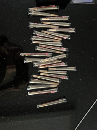 Customer's numerous 24K Hybrid Infused Top Shelf pre-rolls arranged on a dark, reflective surface.