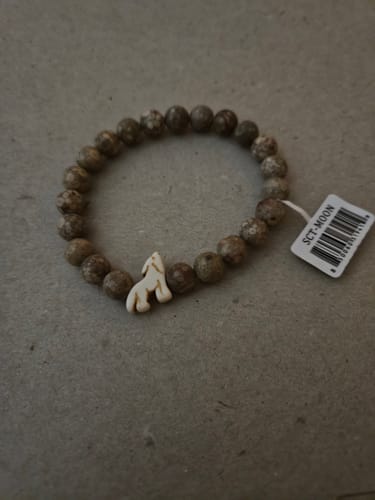Customer's Scout bracelet featuring brown stone beads and a white, three-dimensional wolf charm.