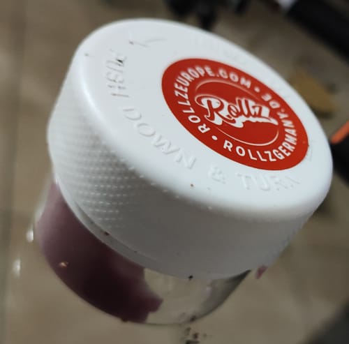 Customer's close-up of a white child-resistant cap from a Rollz THC-A Pre-Roll Cali Blend container