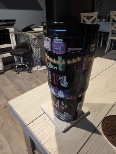 Customer's Bumper Buddy tumbler with spooky Halloween graphics on a black surface sitting on a table.