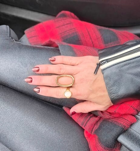 Customer's hand wearing the gold Moonwave Ring over a red plaid sleeve.