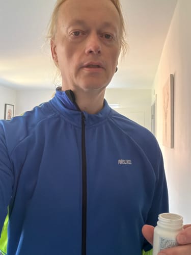 Flacon de gélules Pure NMN du client tenu par une personne dans un cadre domestique.