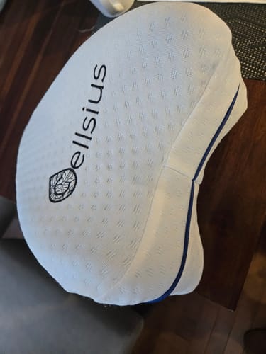 Reviewer's white Cellsius orthopaedic knee cushion, showcasing its contoured shape and branded logo.