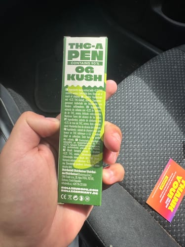 Customer's hand holding the green THC-A Vape packaging inside a car.