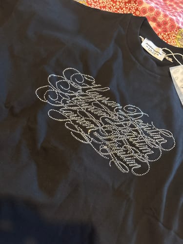 Customer's Radikal Merch Hayran Değilim siyah tshirt, taş baskılı yazı detayı ile yakın çekim.