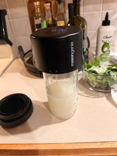 Customer's black Vacuum Genie sealer lid resting on a glass jar on a kitchen counter.