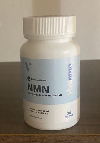Flacon blanc de gélules Pure NMN du client sur une surface sombre.