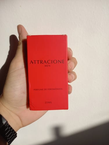 Customer's hand holding a rectangular red box of Attracione Men perfume for pheromones