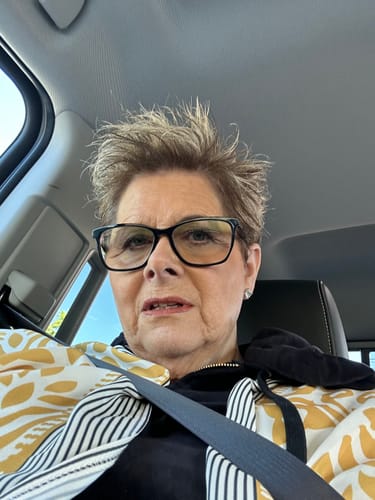 Reviewer in a vehicle wearing a patterned jacket, referencing their use of Koriderm Time Reverse Cream.
