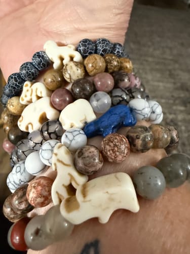 Reviewer's arm wearing a large collection of colorful Fahlo Monthly Club beaded animal bracelets.