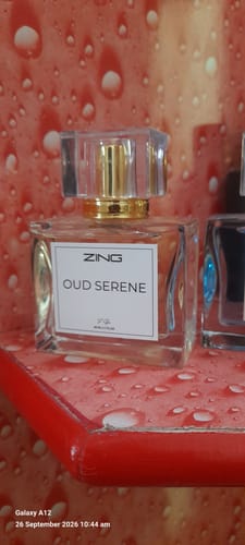 Customer's Oud Serene perfume bottle from the Signature Perfumes bundle, close-up on a red textured surface.