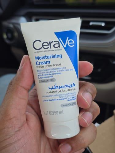 Customer's hand holding a 50ml tube of CeraVe Moisturizing Cream while inside a vehicle.