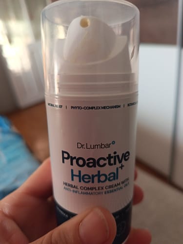 Customer's hand holding a white bottle of Proactive Herbal+ cream for muscle and joint care.