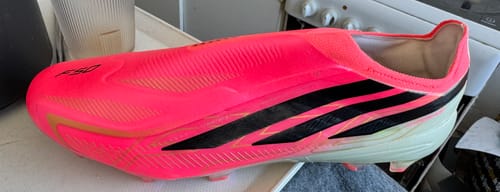 Customer's Adidas F50 Hyperfast Elite laceless football boot in vibrant neon pink, black, and gold colorway.