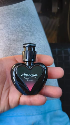 Reviewer's hand holding a small black heart-shaped Attracione perfume bottle, incorrect product received.