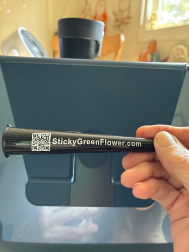 Customer's hand holding a black Colombia Gold pre roll tube with website URL and QR code printed on it.