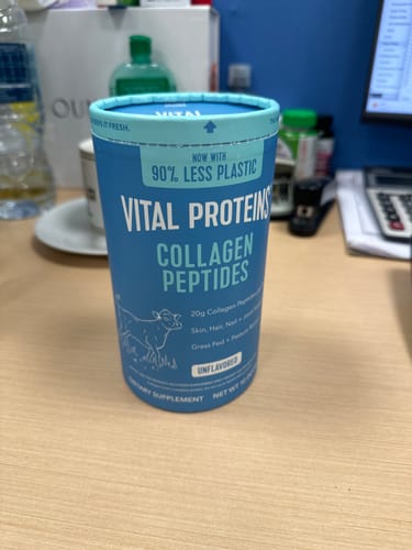 صورة لمستخدم يعرض عبوة Vital Proteins Collagen Peptides الزرقاء الأسطوانية على مكتب عمل.