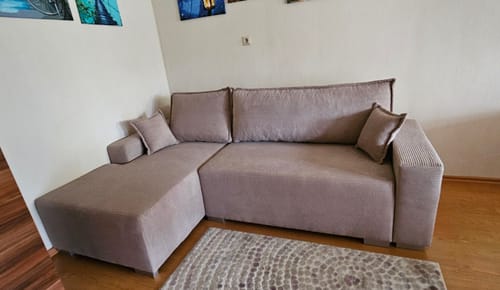 Customer's šviesiai rudas minkštas kampas Bruno svetainėje su pagalvėlėmis ant grindų.