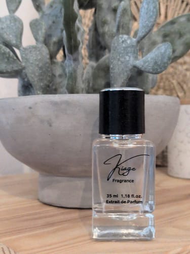 Kundenfoto des Kiage 229 Extrait de Parfum Flakons vor einer Pflanze in einem grauen Übertopf.