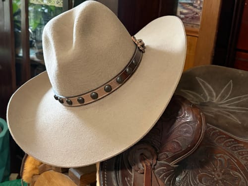 Customer's Broken Bow 4X felt cowboy hat resting on a decorative leather saddle.