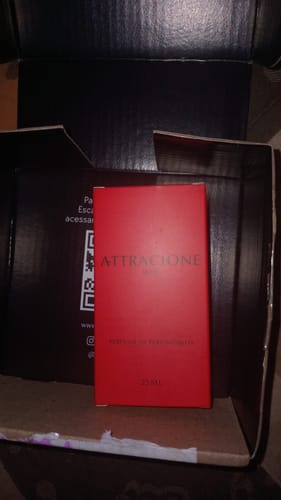 Customer's Attracione Men perfume box in red, inside an open shipping container.