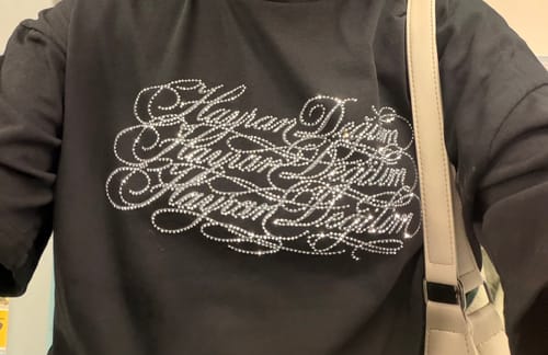 Müşterinin üzerinde parlayan taş detaylı, siyah Radikal Merch Hayran Değilim tshirt