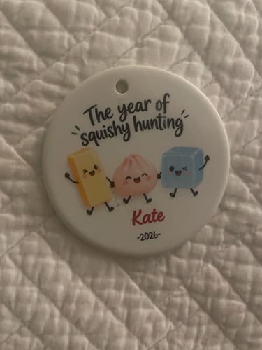 Customer's personalized ceramic ornament titled The Year of Squishy Hunting featuring three cute characters, name, and year.