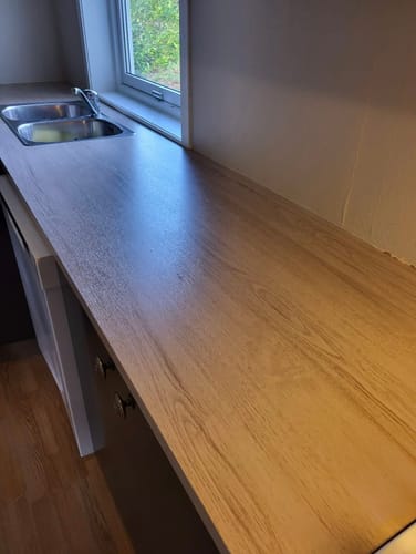 Reviewer's Oak minimal kontaktplast påført en kjøkkenbenk, viser trestruktur og lys overflate.