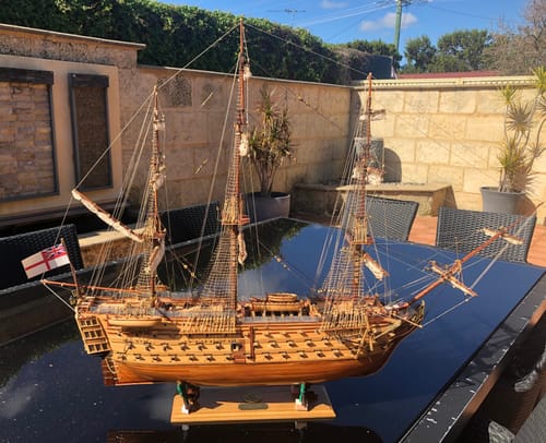 Customer's Soleil Royal wooden model ship displayed on a black outdoor table in a sunlit patio.