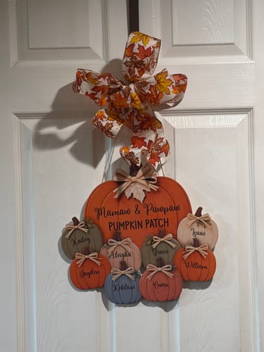 Customer's Grandma & Grandpa’s Pumpkin Patch door hanger, hanging on a white door with a festive leaf bow.