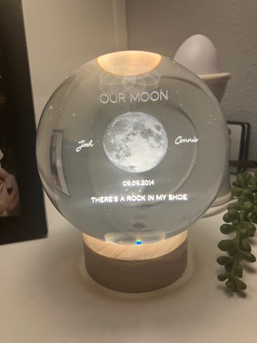 Customer's Personalized Moon Phase Crystal Ball Night Light on a lit wooden base, showing engraved date and names.